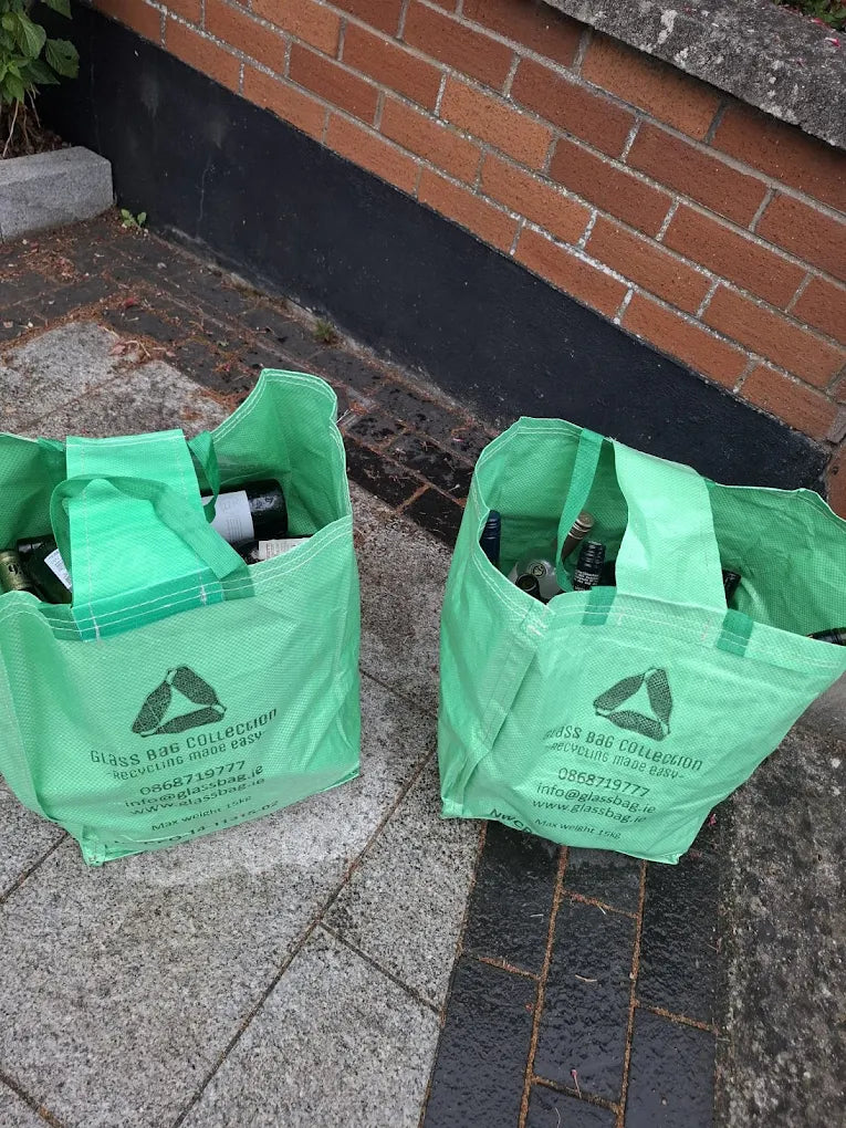 Two reusable GlassBag collection bags filled with bottles and jars on collection day in Ireland.