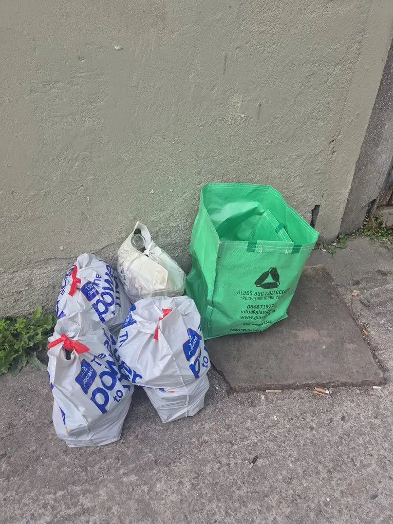 Supermarket bags of glass bottles beside a green GlassBag, the doorstep alternative to a Dublin bottle bank run.